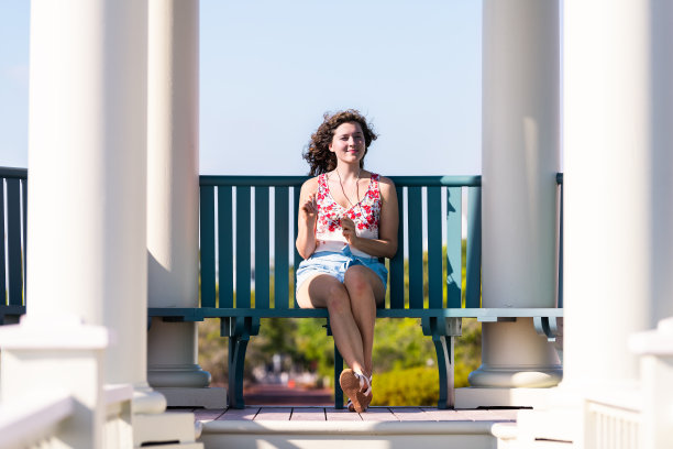 在阳光明媚的日子里，坐在长椅上的年轻女孩触摸着佛罗里达景色中的项链图片下载
