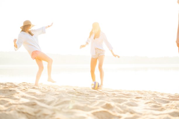 一群年轻人在海滩上玩球。年轻的朋友们在沙滩上享受暑假图片下载