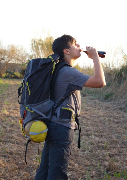 男孩背着露营背包喝苏打水照片图片下载