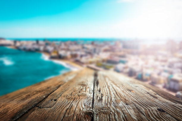 模糊的海岸线，碧绿的海洋。蓝色的木桌，为您的装饰和广告产品提供空间。图片下载