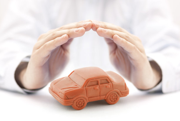 汽车保险概念与橙色汽车玩具覆盖的手图片下载