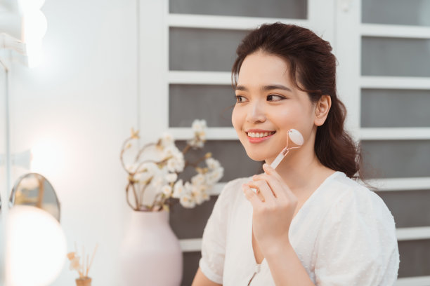 在家用玉石滚轮进行面部按摩的女人素材图片