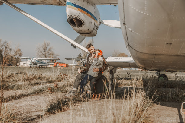 快乐的父母和孩子坐在户外飞机旁图片下载