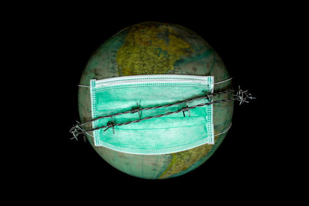 世界或地球独自在外太空戴医用口罩以保护世界免受污染，并以带刺铁丝作为不能离开地球的象征，保护世界的理念，选择聚焦于模糊的地球面具图片下载