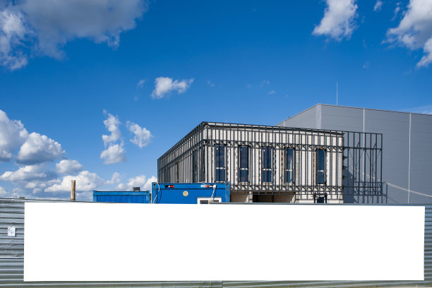 在建工厂围墙上的空白白色广告横幅。在一个阳光明媚的日子里工业区图片下载