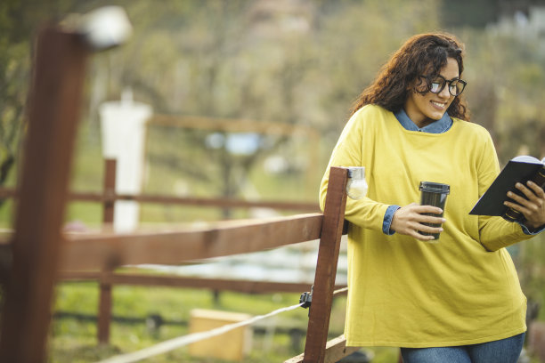 年轻女子在自然中放松与书和喝咖啡图片下载