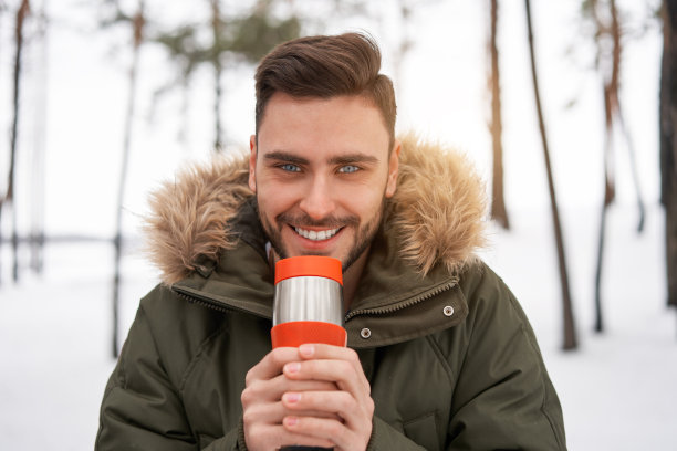 站在冬季森林里靠近汽车的迷人白人男子图片下载