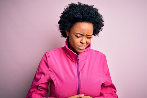 年轻的非裔美国女运动员，卷发，穿着运动服，因消化不良手捂肚子，感到不适图片下载