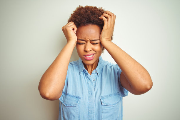 年轻漂亮的非裔美国妇女因头痛而痛苦，感到绝望和压力，双手抱头图片下载