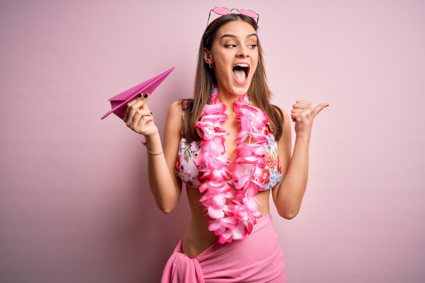 年轻美丽的女人度假穿着比基尼和夏威夷花环纸飞机指向和显示拇指向上到一边与快乐的脸微笑图片下载