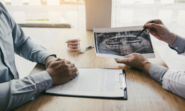 亚洲的年轻牙医正在为病人讲解牙根治疗。图片下载