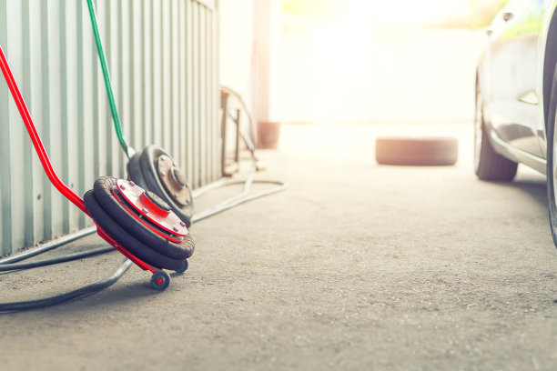 汽车轮毂修理店户外地面。在车间更换冬季轮胎。汽车轮胎的维修、检查和保养。汽车车库配有充气气动千斤顶。Copyspace文本图片下载