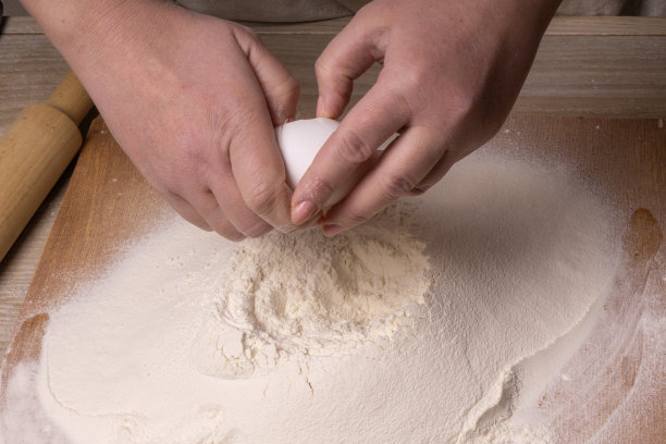 面粉撒在桌子上，上面有一个鸡蛋，用来做生面团。图片下载