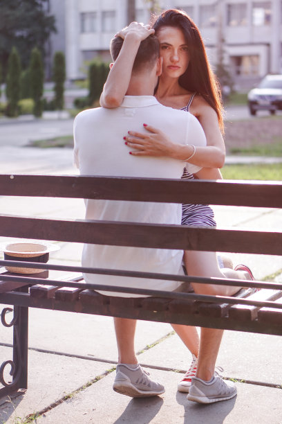 一对漂亮的男女坐在阳光下的长凳上。一个女孩和一个男孩的浪漫主题。春天，夏天照片关系，爱情，情人节图片下载