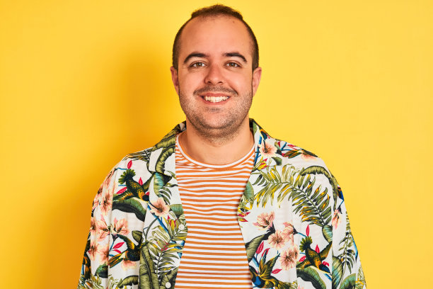 度假的年轻人穿着夏天的t恤条纹t恤孤立的黄色背景与一个快乐和凉爽的微笑在脸上。幸运的人。图片下载