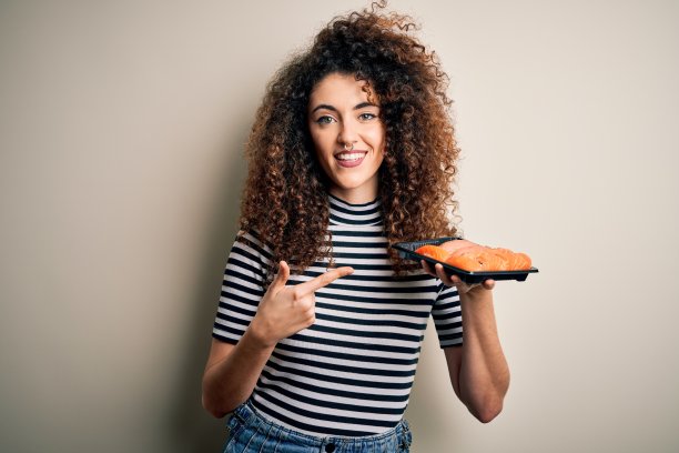年轻美丽的女人与卷发和穿孔持有托盘新鲜寿司非常幸福的指与手和手指图片下载