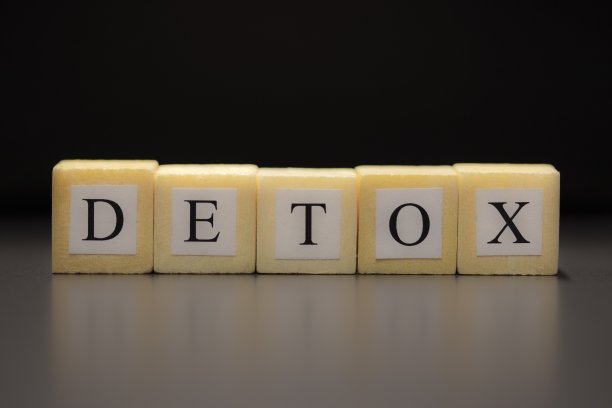 “排毒”这个词写在孤立在黑色背景下的木方上……图片下载