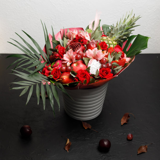 原来不寻常的花束玫瑰，兰花和各种红色水果在黑色的背景图片下载