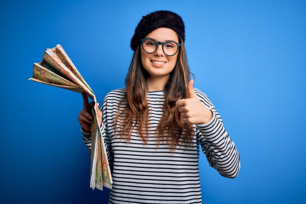 年轻美丽的女游客度假戴眼镜和贝雷帽拿着城市地图开心地笑着做ok的手势，拇指与手指竖起，优秀的手势图片下载