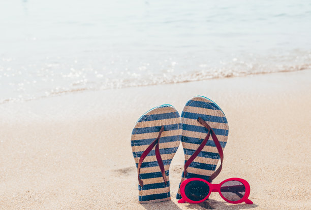 墨镜和人字拖在热带沙滩上。旅游、度假的概念。图片下载
