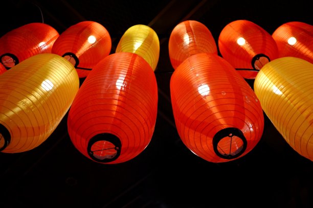 一排红黄相间的中国灯笼挂在电线上，灯泡在黑暗的夜晚闪闪发光图片下载