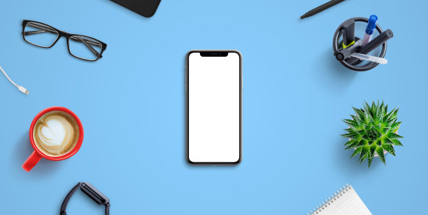 蓝色办公桌上放着手机模型，周围摆满了办公用品。独立的屏幕用于模型，网站或应用演示。上vie，平躺图片下载