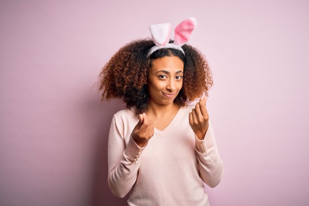 戴兔耳朵的非洲裔年轻女人做要钱手势图片下载