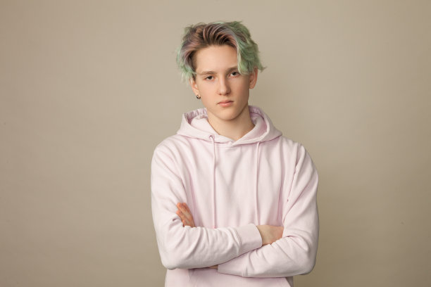 一个十几岁男孩的工作室肖像与绿色的头发在米色的背景图片下载