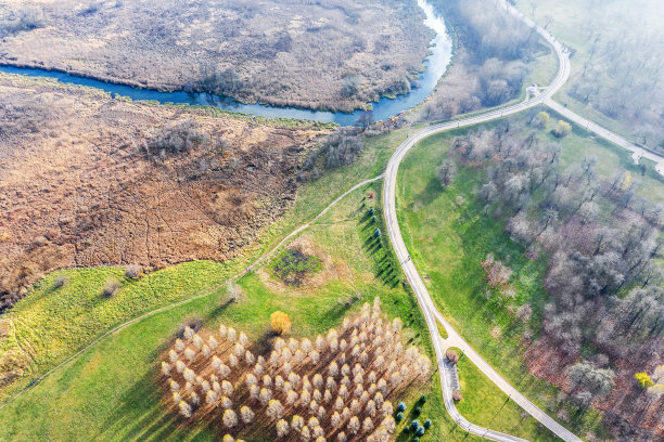 蜿蜒的自行车道在绿色的草坪和树木之间。秋天的公园景观。航拍照片图片下载