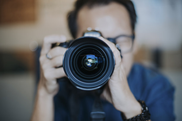 在办公室查看单反相机收藏的中国男摄影师图片下载