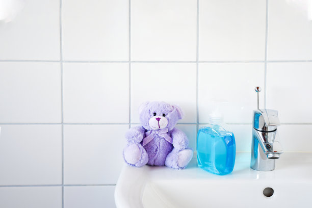 家庭护理形象浴室盥洗盆，tab水和一瓶蓝色酒精凝胶洗手液，以及保护家人免受冠状病毒(COVID-19)感染的熊玩具。图片下载
