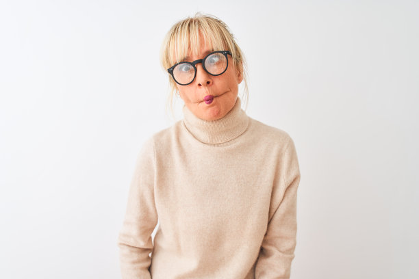 在白色背景下嘟着嘴，做出滑稽表情的中年妇女。有趣的表情。图片下载
