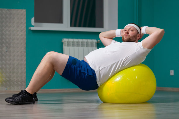 在健身课上，一名超重男子正躺在健身球上。胖子看起来很失望，因为减肥训练的效果不好图片下载
