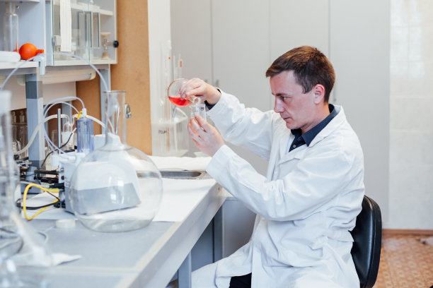 年轻男性科学家在实验室用液体进行化学实验图片下载