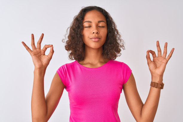 穿着粉色T恤的年轻巴西女性，在白色背景前放松地微笑，冥想图片下载