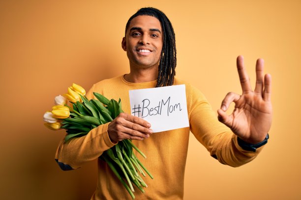 非裔美国人拿着最好的妈妈短信纸和郁金香，用手指做ok手势庆祝母亲节，很好的象征图片下载