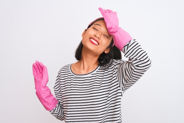 年轻的中国清洁工用手套清洁孤立的白色背景，强调用手顶在头上，震惊的羞愧和惊讶的脸，愤怒和沮丧。为错误而恐惧和不安。图片下载