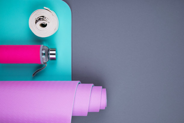 顶视图的蓝色粉色瑜伽垫，玻璃水瓶和扭曲的白色带在灰色的背景。图片下载
