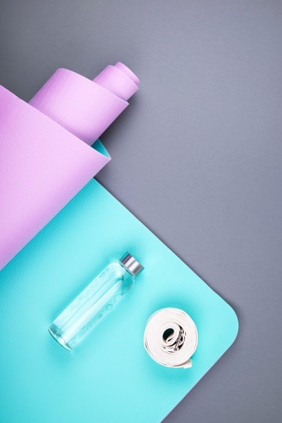 顶视图的蓝色粉色瑜伽垫，玻璃水瓶和扭曲的白色带在灰色的背景。空间的文本。图片下载
