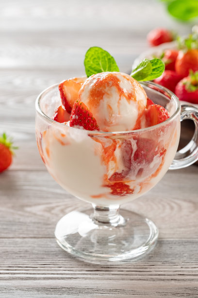 美味的奶油冰淇淋与草莓，倒在一个玻璃杯的甜糖浆在一个轻的背景图片下载