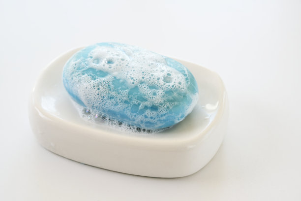 白色肥皂盘上带泡沫的蓝色肥皂条，预防病毒感染的保健和卫生概念，复制空间图片下载