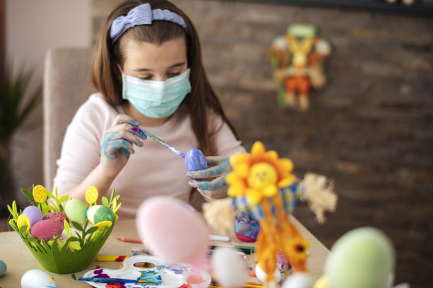 女孩用防护面具画复活节彩蛋。病毒防护的概念。候的照片图片下载