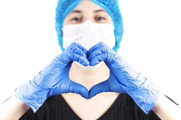 戴医用口罩的女医生外科护士用手做心脏。图片下载