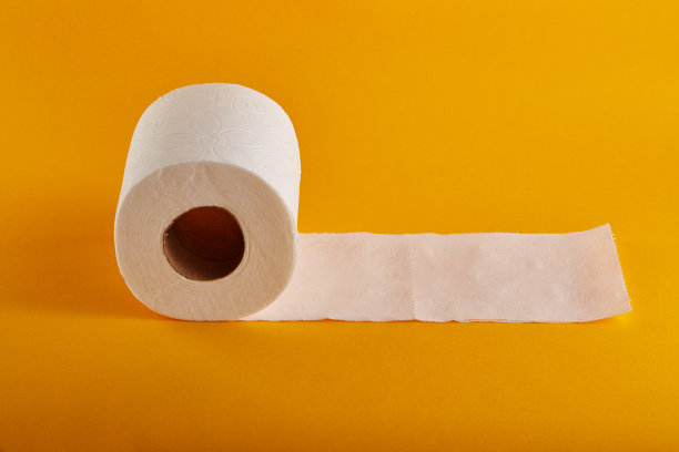 白色卫生纸卷上鲜艳的黄色/橙色背景图片下载