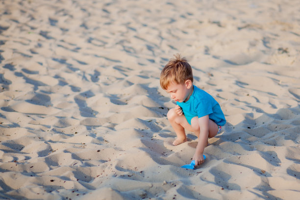 男孩在沙滩上玩。孩子们在海边玩暑假家庭度假。沙滩和水上玩具，儿童防晒产品。小男孩在海边挖沙子，建城堡。图片下载