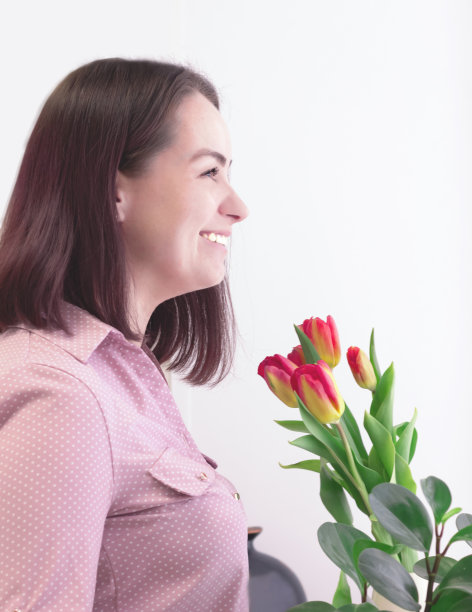 办公室里的漂亮女商人。带着郁金香微笑的中年女人。图片下载