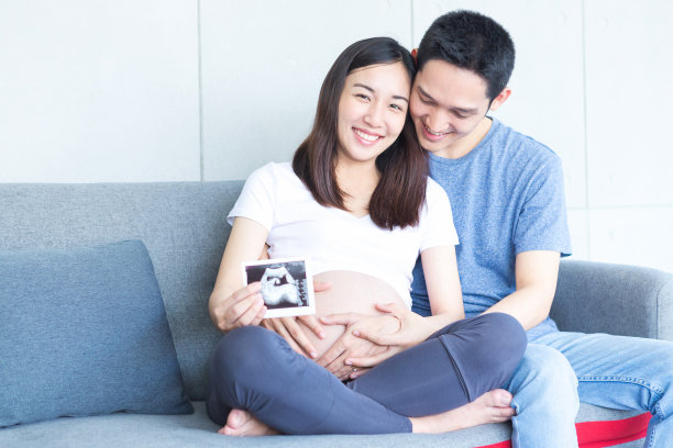 妈妈和爸爸抱着宝宝的超声波照片。妈妈和爸爸微笑着展示他们胎儿的超声波图像。新出生的。图片下载