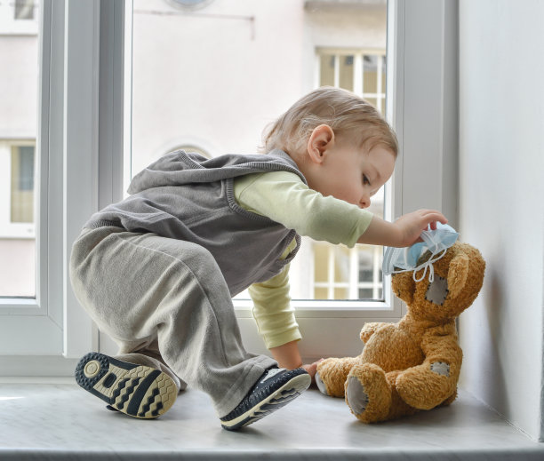 在冠状病毒和流感爆发期间，被隔离的儿童在窗口与生病的泰迪熊玩耍。2019冠状病毒病概念图片下载