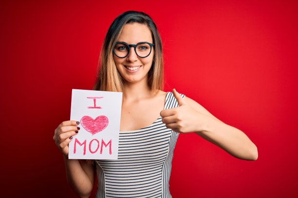 年轻美丽的女人拿着纸与爱妈妈短信庆祝母亲节快乐与大微笑做ok手势，拇指与手指竖起，优秀的手势图片下载