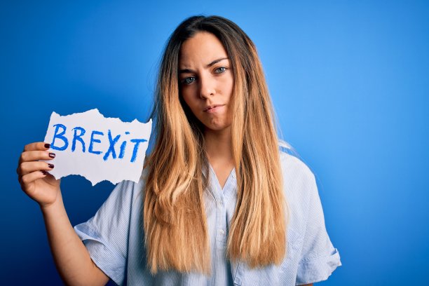 年轻漂亮的金发碧眼女子举着英国脱欧的旗帜，聪明的脸上充满自信，思考严肃图片下载